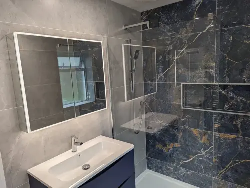a Newtown Lane bathroom with mirror, glass shower door and sink