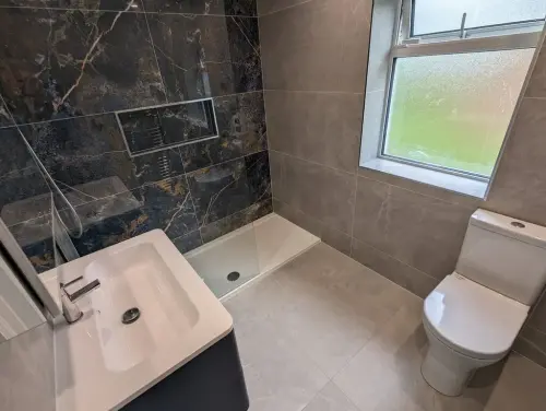 a Newtown Lane bathroom with a shower sink and toilet