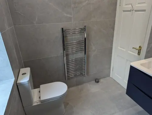 a Newtown Lane bathroom with a toilet, white door and a sink